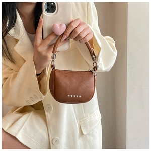 Détail du mini sac selle en cuir marron grainé avec clous métalliques en étoile
