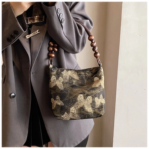 Detail of butterfly jacquard fabric and vintage round wooden bead handle on handbag