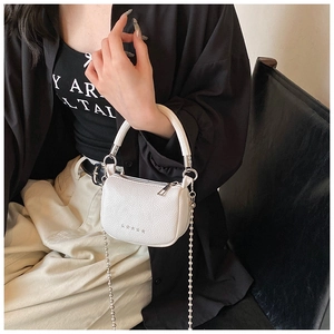 Détail du mini sac selle blanc texturé avec clous en étoile et bandoulière chaîne à billes