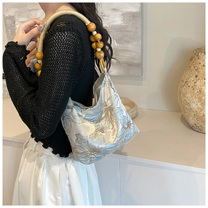 Detail of silver floral embroidery underarm bag with vintage wooden bead shoulder strap