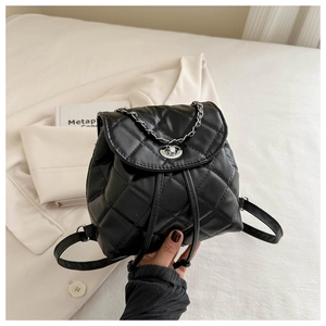 Detail of black quilted leather backpack with silver chain and turn-lock closure