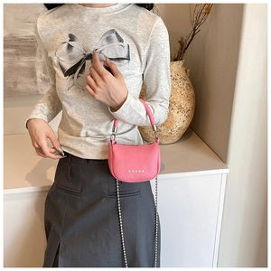 Gros plan du mini sac selle rose avec clous étoiles et chaîne à billes argentée