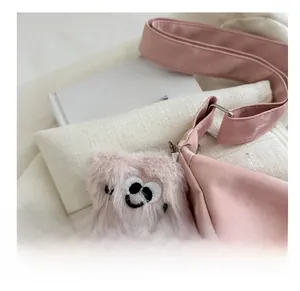 Gros plan détaillé d'un sac cabas rose en daim avec un pendentif monstre en peluche
