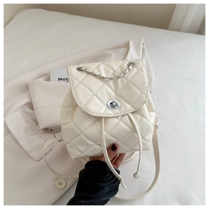Detail of cream quilted mini backpack with silver twist lock and delicate chain straps