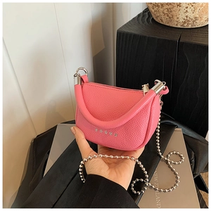 Détail d'un sac selle en cuir grainé rose avec rivets étoiles et chaîne à billes argent