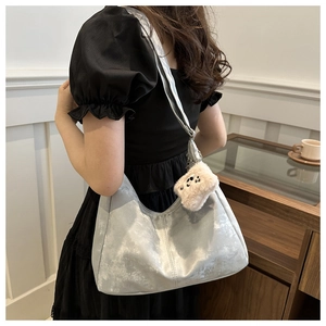 Sac hobo argenté métallisé avec pendentif panda en peluche sur une robe noire chic