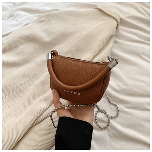 Gros plan d'un sac à main marron en cuir grainé avec rivets en étoile et chaîne bille