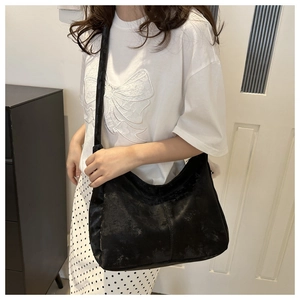 Sac hobo minimaliste en daim noir avec large bandoulière porté par un mannequin