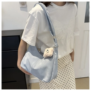 Détail d'un sac hobo en velours bleu clair avec pendentif chat en peluche