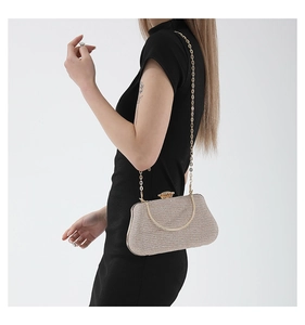 Champagne gold glitter clutch bag with metal handle and chain strap on a black dress