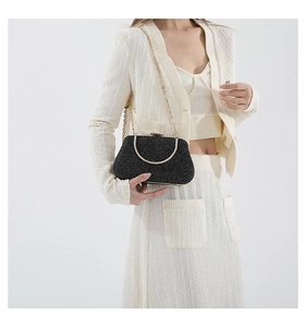 Detail of black glitter evening clutch featuring golden ring handle and chain strap
