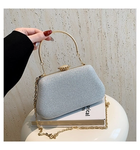 Detail of silver glitter evening clutch with golden ring handle and chain strap