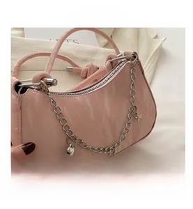 Gros plan du sac croissant rose avec poignée nouée et chaîne à breloques argent