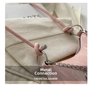 Détail du sac en cuir verni rose motif croco avec chaîne et pendentif en cœur