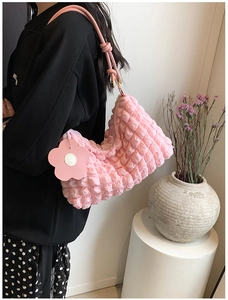 Detailed close-up of pink puff textured cylinder bag with floral charm and knot strap