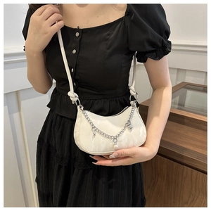 Détail du sac demi-lune blanc avec chaîne argentée et pendentif perle porté par un mannequin