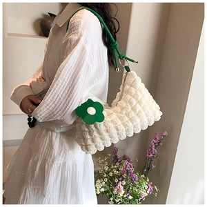 Close-up of white bubble texture nylon bag with green rope strap and flower charm