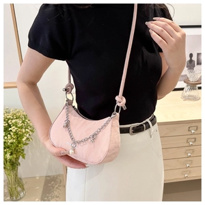 Roze zadeltas met zilveren ketting, parelsterren en crossbodyband gedragen door een model