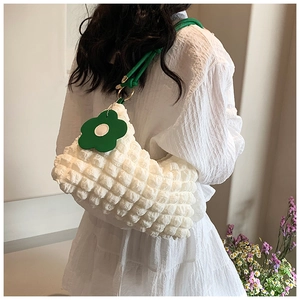 Detail of white popcorn texture shoulder bag with green strap and flower charm