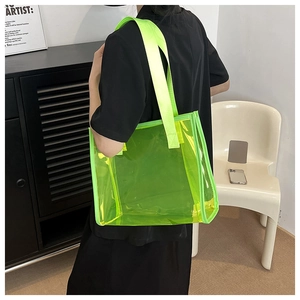 Neon green transparent PVC tote bag with wide straps shown on woman shoulder in detail