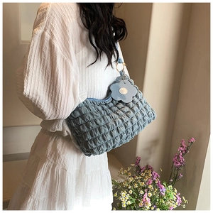 Detail of blue bubble texture shoulder bag featuring a light blue floral charm and strap