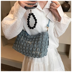 Close-up of light blue bubble textured shoulder bag with black bead charm detail