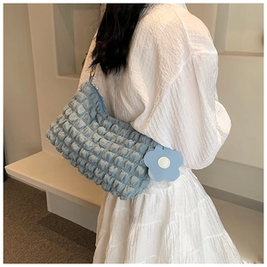 Close-up of light blue bubble textured shoulder bag with a floral charm on model