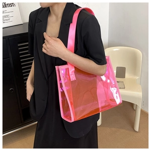 Close-up of pink transparent PVC tote bag with sturdy handles on a model in black suit