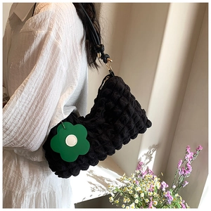 Detail of black quilted cloud bag with unique bubble texture and green flower charm