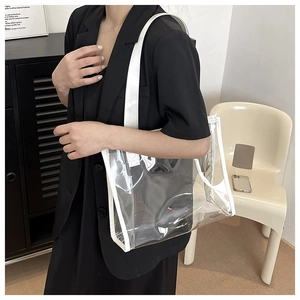 Detail of transparent PVC tote bag with white canvas straps shown on shoulder