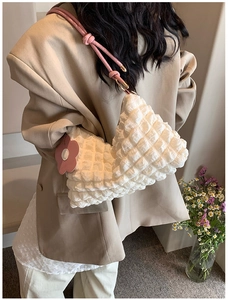 Detail of white popcorn texture shoulder bag with pink rope strap and floral charm