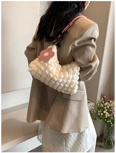 Detail of white bubble texture fabric shoulder bag with pink floral charm and handles