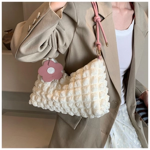 Detail of white bubble texture tote bag with pink floral charm and knot shoulder strap