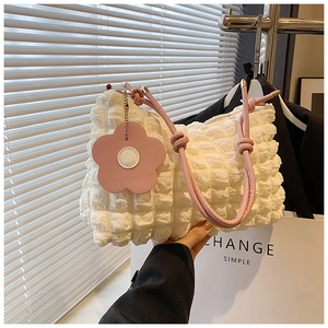 Detail of off-white pleated handbag with pink braided knot handle and floral charm accessory