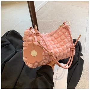 Detail of pink popcorn textured handbag with flower charm and golden hardware