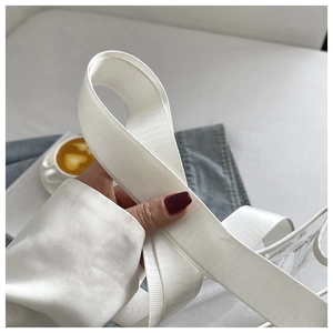 Detail of white wide woven shoulder strap on a clear PVC bag for daily casual use