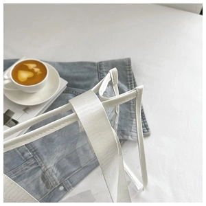 Detail of transparent PVC tote bag with white reinforced stitching and woven handles