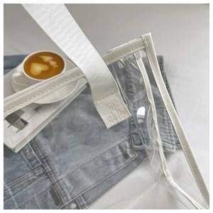 Close-up of X-shaped reinforced stitching on white handles of a clear PVC tote bag