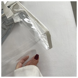 Close-up of transparent PVC tote bag with white leather trim and detailed stitching