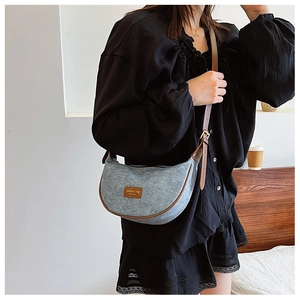 Detail of grey felt half-moon bag with brown leather trim and antique bronze hardware