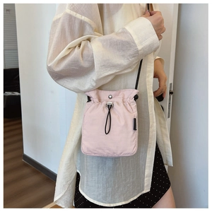 Detail of pink nylon crossbody bag featuring drawstring closure and silver metal snap button