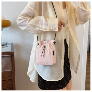 Detail of light pink drawstring crossbody bag featuring a FASHION side label