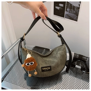 Detail of army green canvas hobo bag with black leather straps and plush monster charm