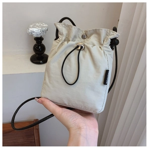 Detail of a minimalist cream nylon drawstring crossbody bag with Fashion logo tag