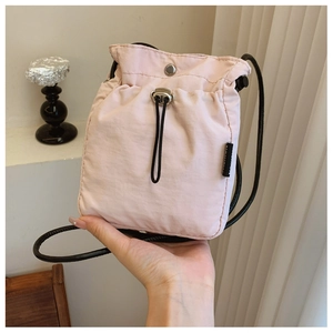 Detail view of pink mini drawstring nylon crossbody bag with metallic snap button closure