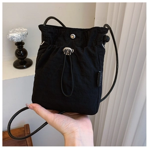 Detail of black nylon drawstring crossbody bag with adjustable silver buckle and crinkle texture