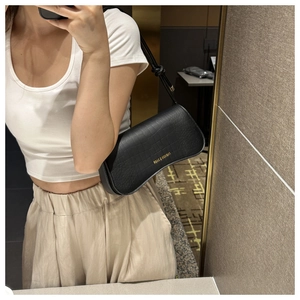 Détail d'un sac sous le bras noir à motif crocodile avec logo doré élégant