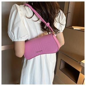 Détail du sac bandoulière rose embossé croco avec bandoulière nouée sur robe blanche