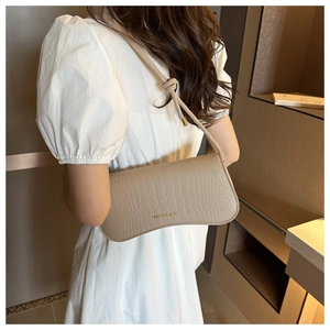 Détail du sac baguette beige à motif crocodile avec bandoulière nouée et dorures