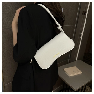 Détail d'un sac sous les bras blanc motif crocodile avec logo en métal doré